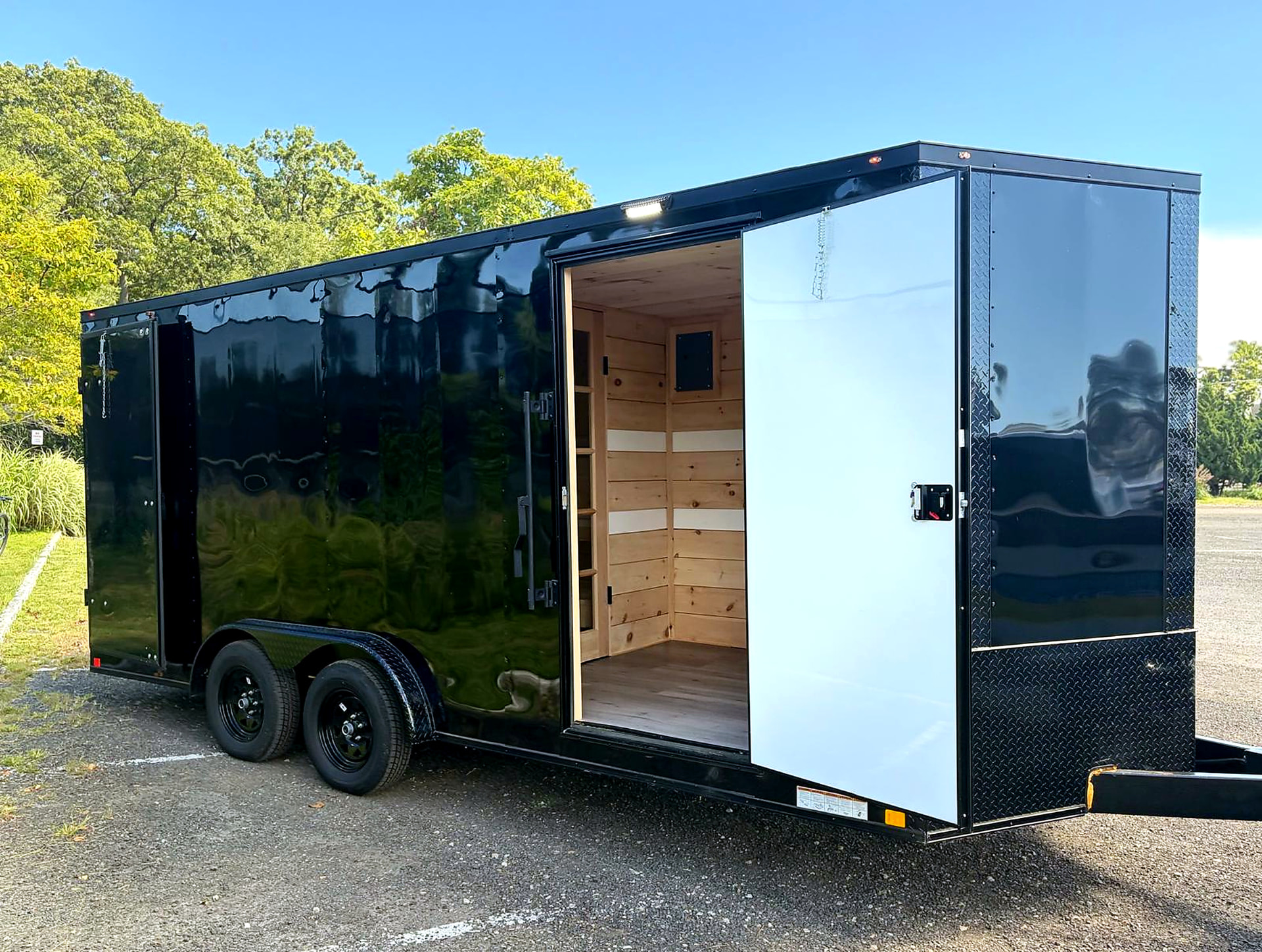 Black Nomad mobile sauna trailer parked outdoors with its entrance open